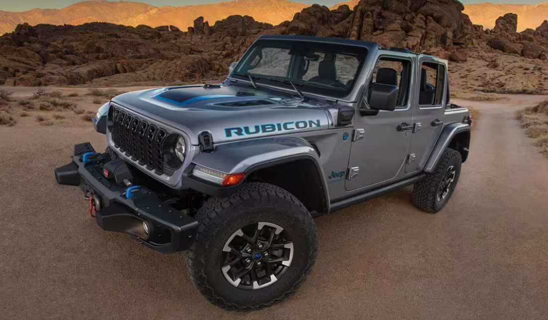 A silver 2024 Jeep Wrangler 4xe in a desert mountain landscape at sunset