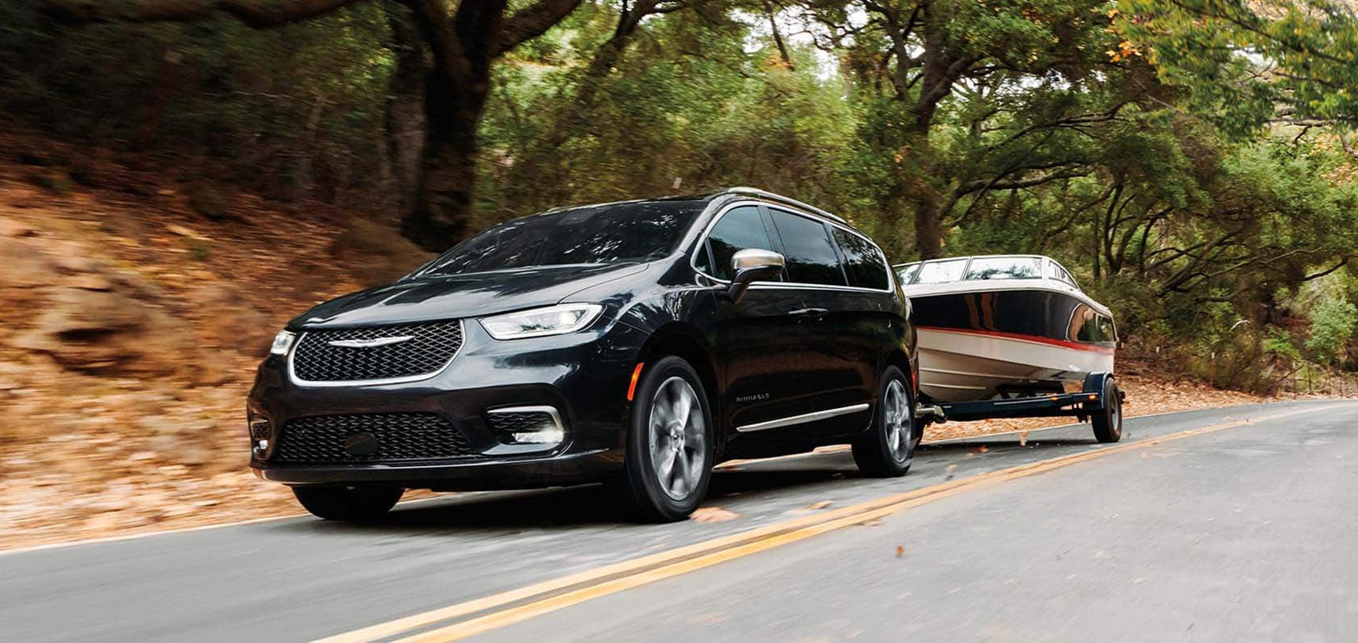 A black 2025 Chrysler Pacifica towing a boat.