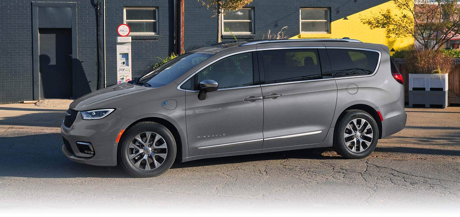 A gray 2025 Chrysler Pacifica Plug-In Hybrid parked by the curb